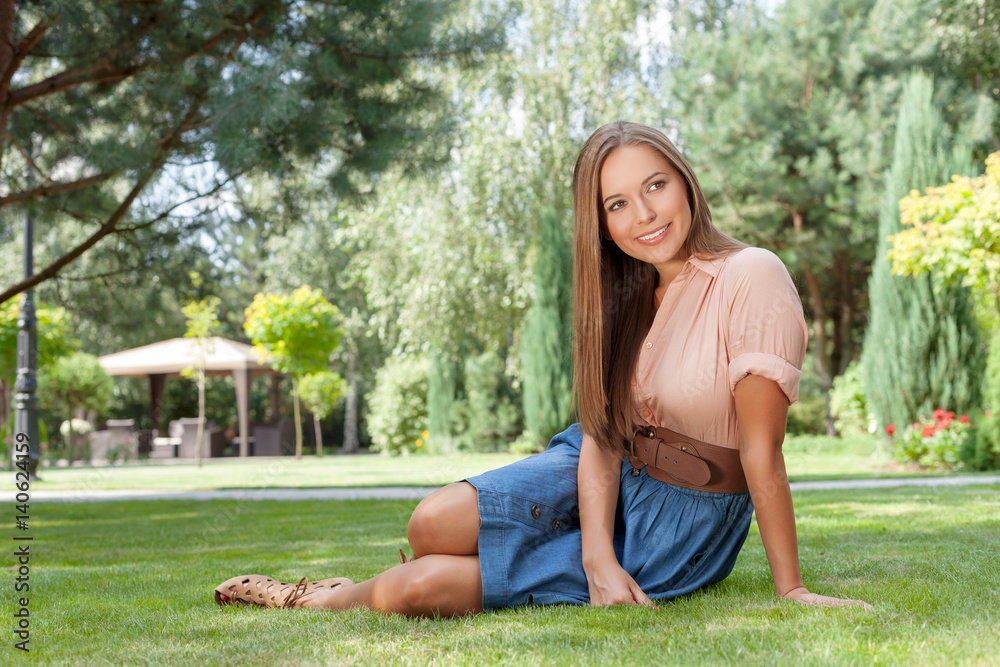 Full length of smiling young woman looking away while relaxing in park