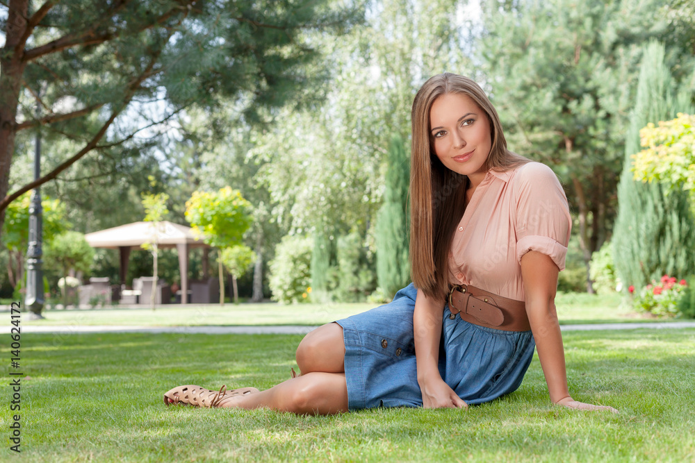 Full length of beautiful young woman looking away while relaxing on grass in park Full length of beautiful young woman looking away while relaxing on grass in park
