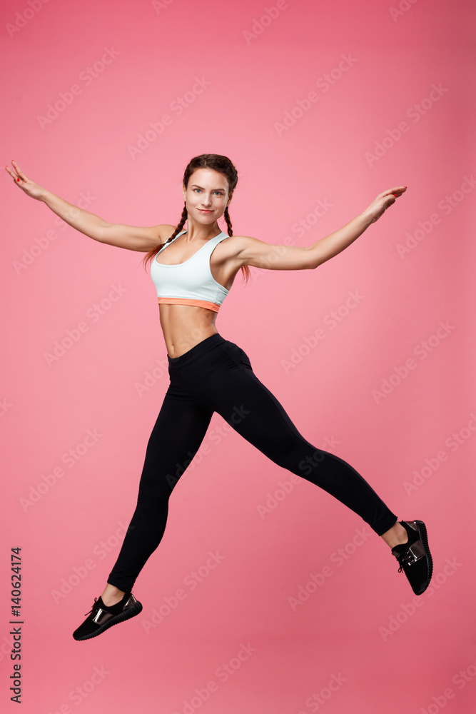 Obraz premium Girl in stylish sport outfit jumpig with wide spread hands