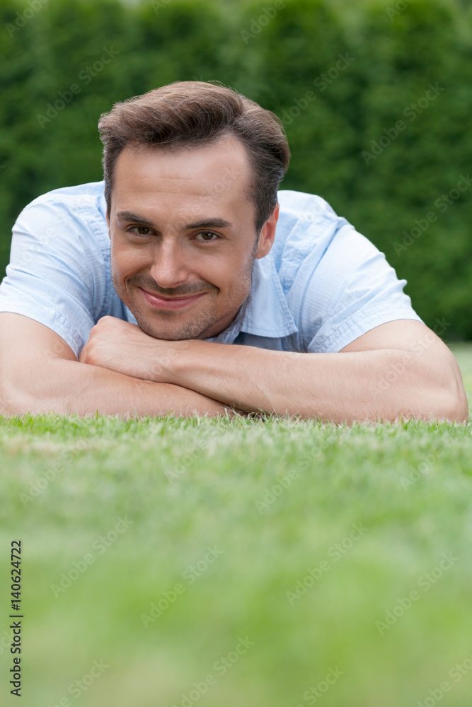 Portrait of smiling young man lying on grass in park Portrait of smiling young man lying on grass in park