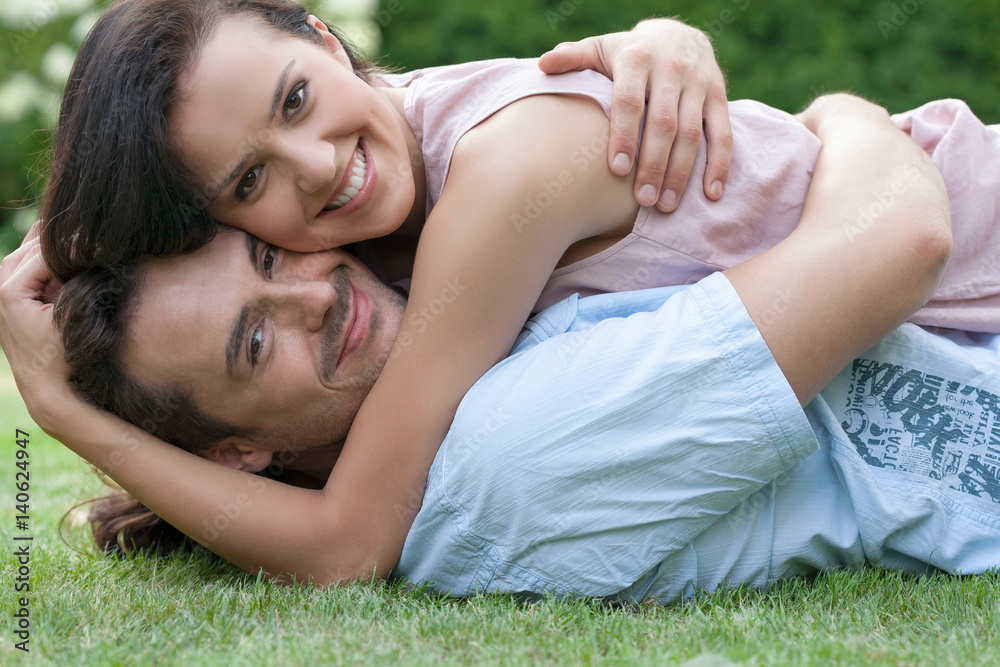 Portrait of smiling young couple embracing while lying in park Portrait of smiling young couple embracing while lying in park
