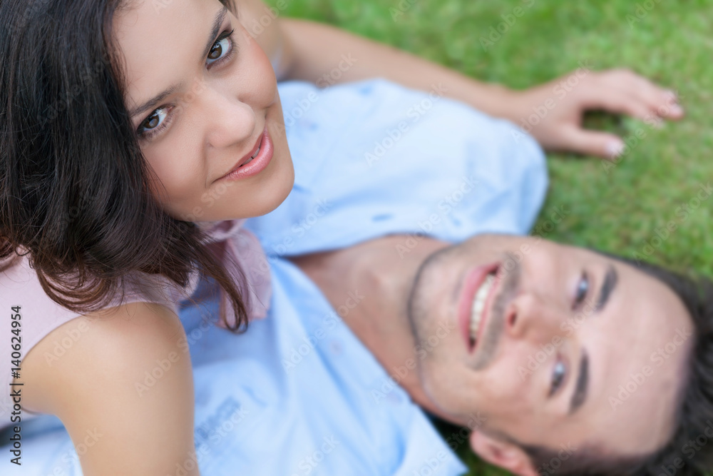 High angle portrait of playful young woman on top of man in park High angle portrait of playful young woman on top of man in park