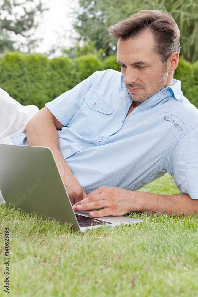 Young man using laptop in park Young man using laptop in park