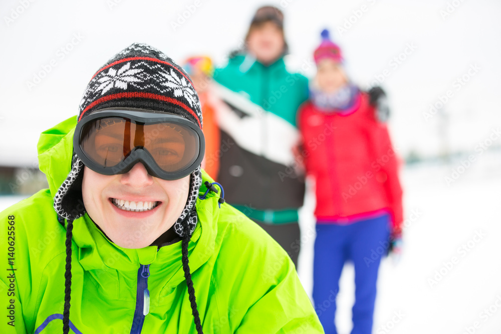 Portrait of smiling young man with friends in background during winter Portrait of smiling young man with friends in background during winter