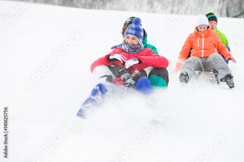 Young couples enjoying sled ride on snow covered slope