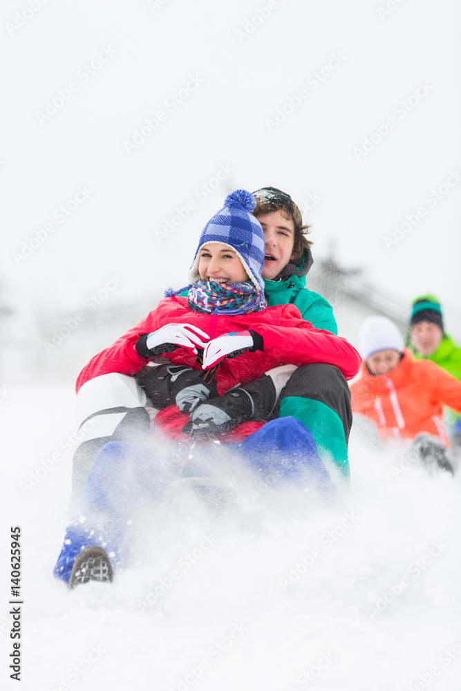 Excited young friends sledding in snow