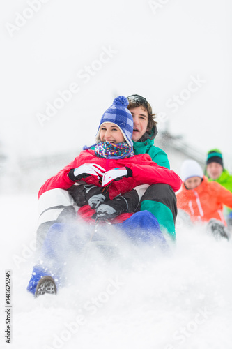 Excited young friends sledding in snow