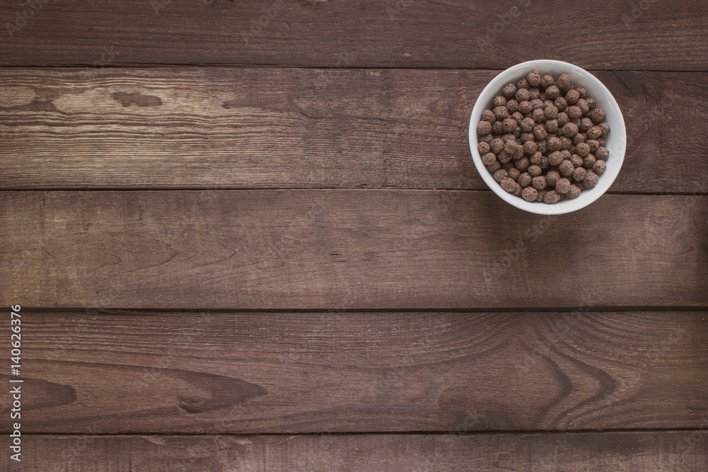 Bowl with cereal chocolate balls on a wooden table . Top view Bowl with cereal chocolate balls on a wooden table . Top view