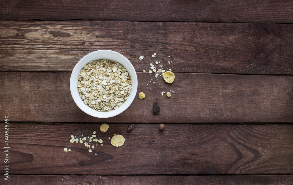 Dry oatmeal in a white bowl on a wooden table Dry oatmeal in a white bowl on a wooden table