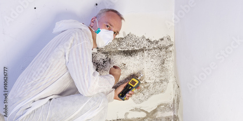 Pest controler gauges a mold infestation photo