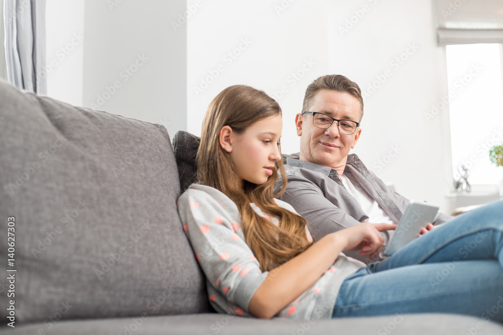 Father and daughter using digital tablet on sofa at home Father and daughter using digital tablet on sofa at home