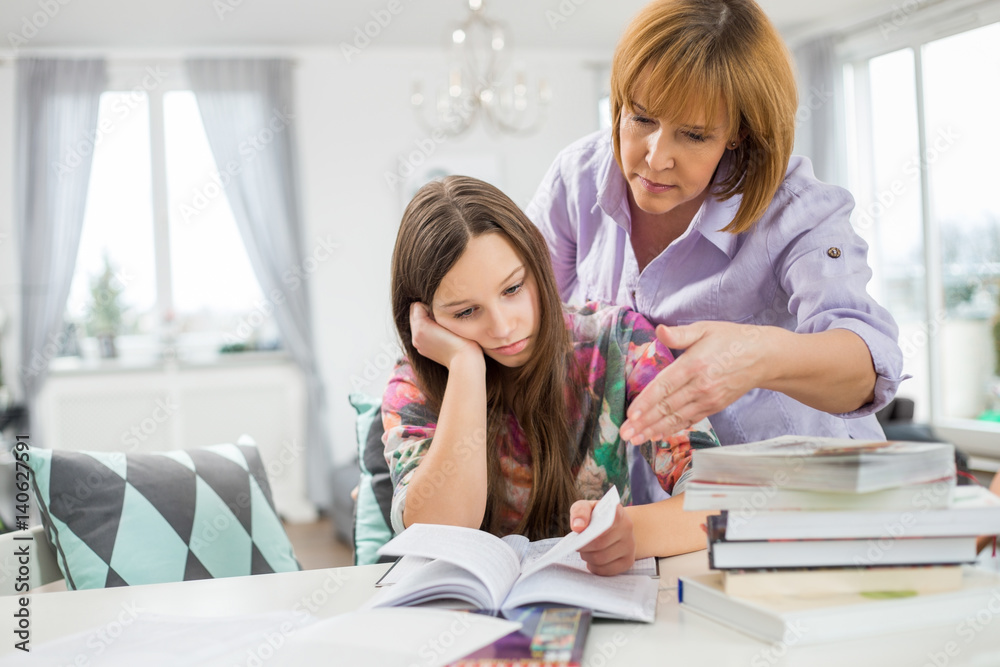 Mother assisting bored girl in studying at home Mother assisting bored girl in studying at home
