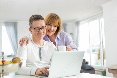 Loving couple using laptop together at home © moodboard