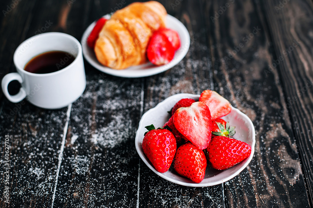 strawberries sprinkled with sugar with a Cup of coffee on a wooden table strawberries sprinkled with sugar with a Cup of coffee on a wooden table