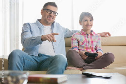 Happy father and daughter playing video game in living room