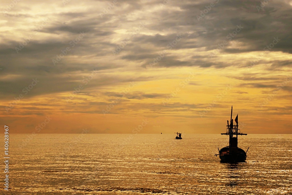 Fishing boat silhouette and sunset ocean background