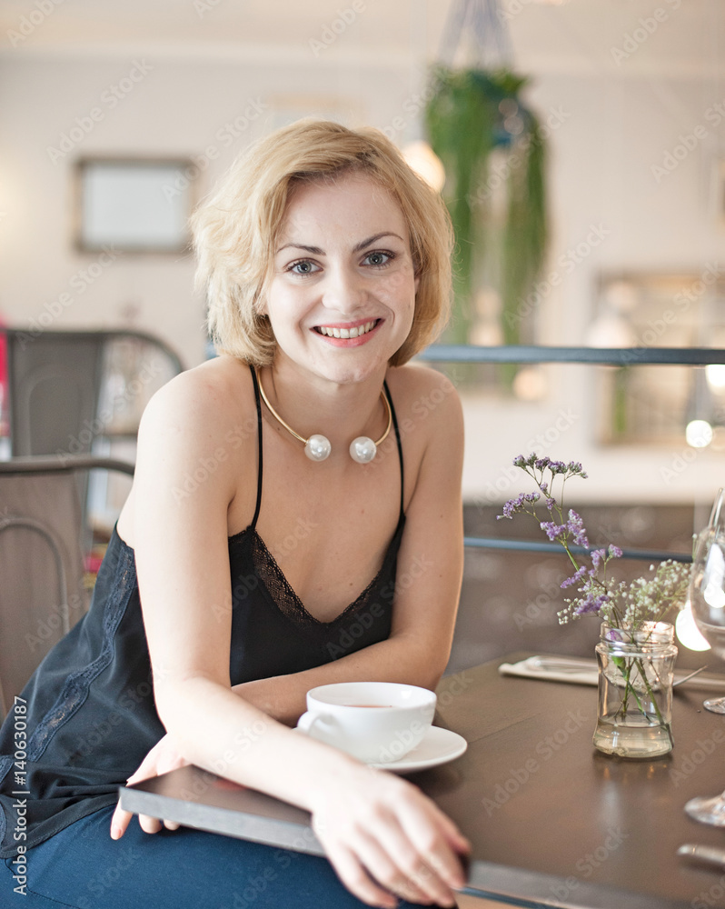 Portrait of happy young woman sitting at restaurant table Portrait of happy young woman sitting at restaurant table