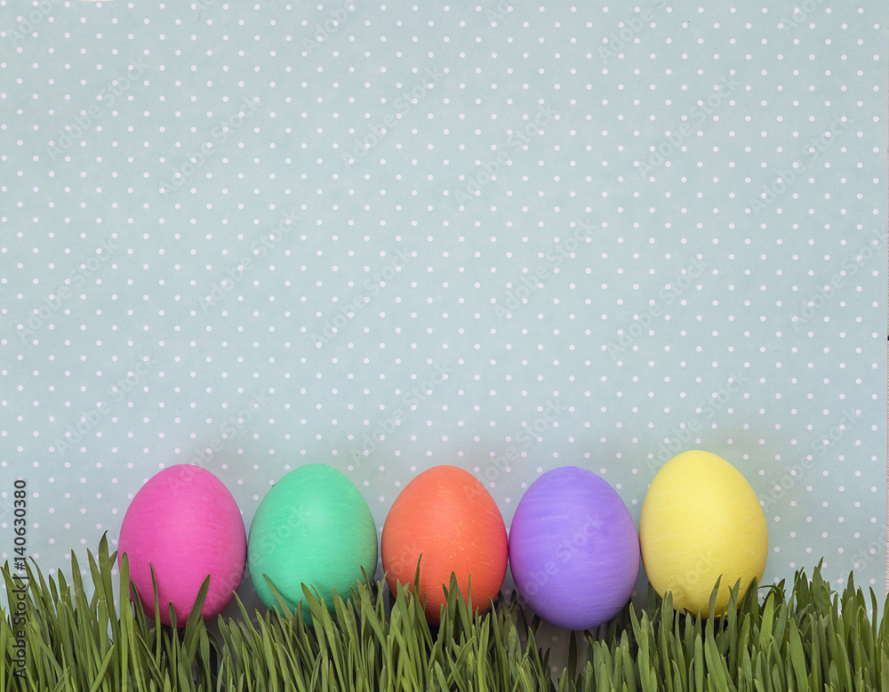 Easter eggs in fresh green grass on background in polka dots.