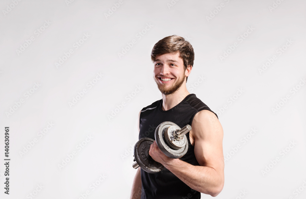 Handsome fitness man holding dumbbell, studio shot.