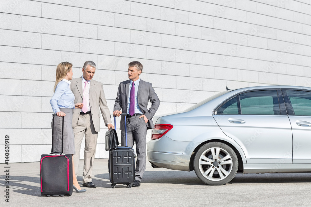 Businesspeople with luggage discussing outside car on street Businesspeople with luggage discussing outside car on street
