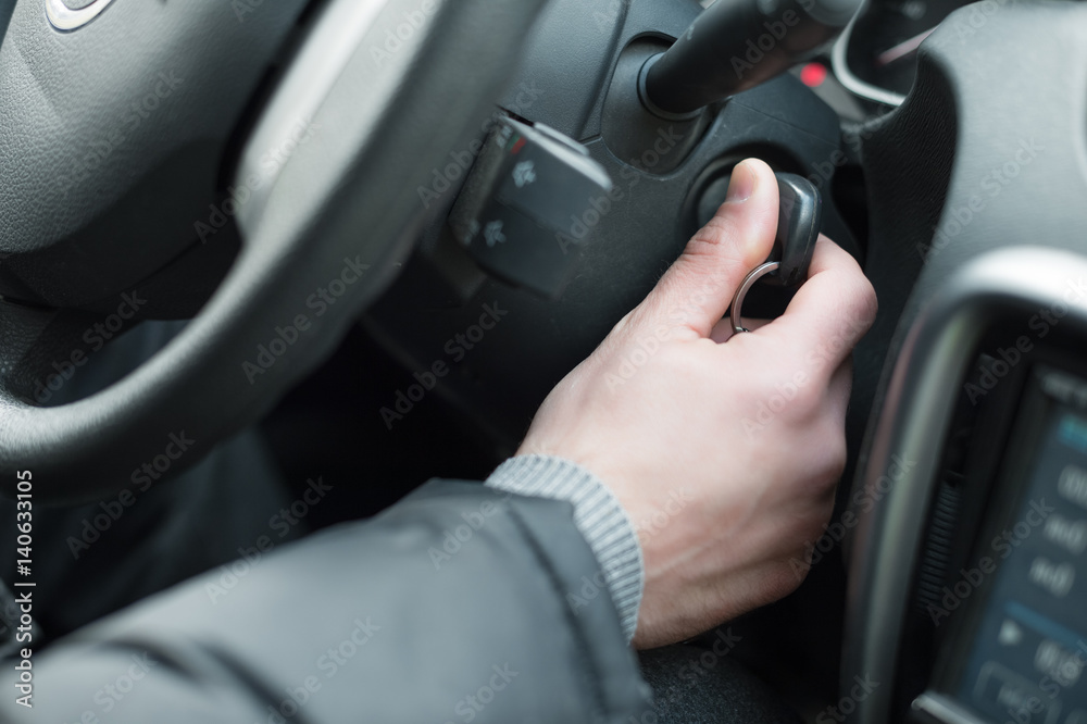 Closeup inside vehicle of hand holding key in ignition, start engine key