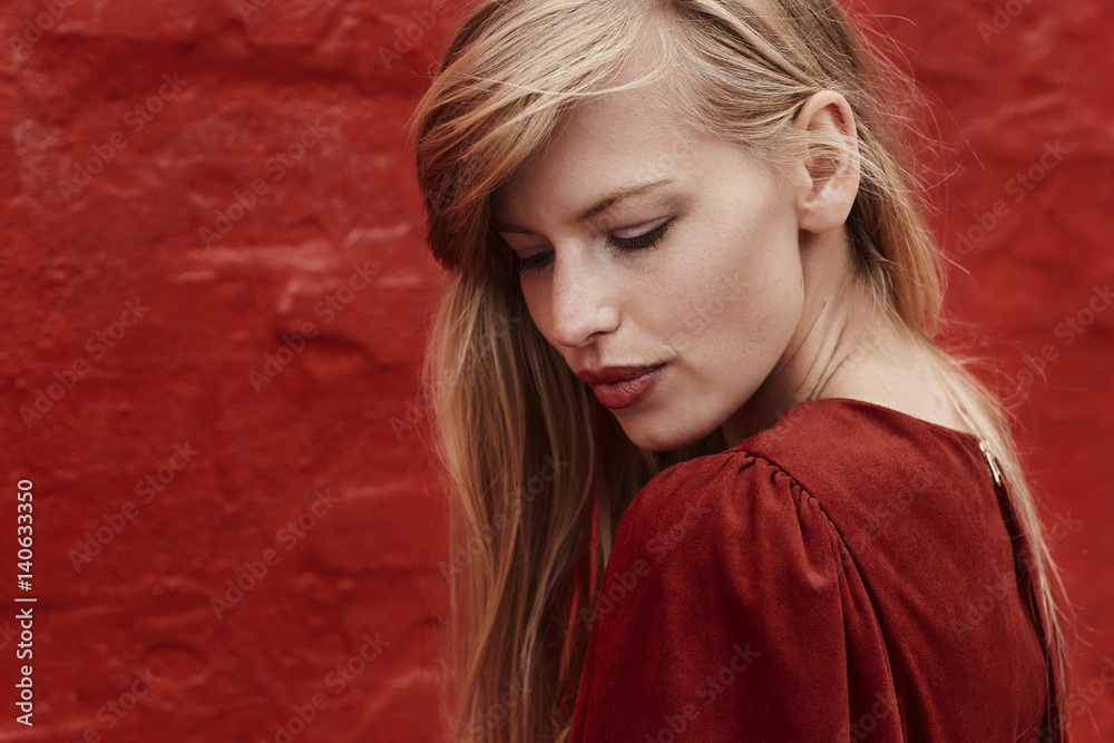 Fototapeta premium Gorgeous blond woman in red dress, looking down