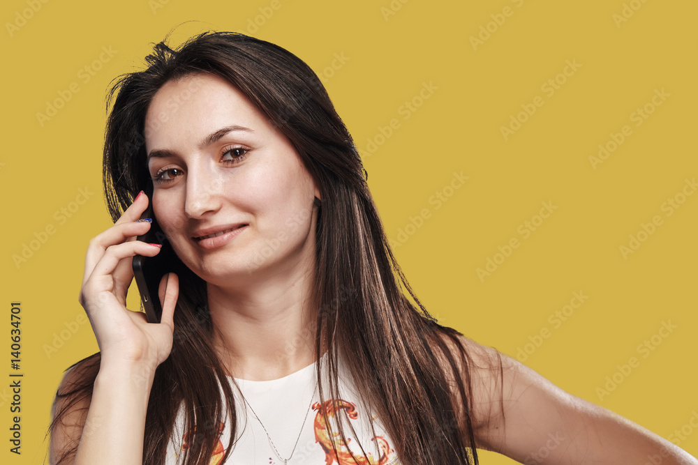 Close up portrait of a smiling young woman while talking on a phone Close up portrait of a smiling young woman while talking on a phone