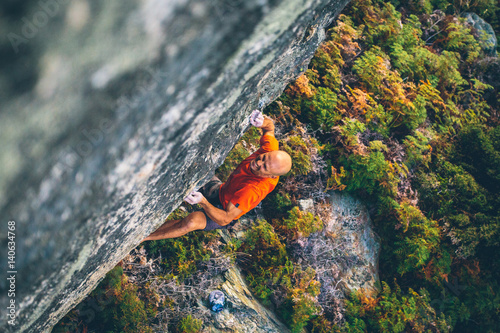 Rock climber with no ropes above green forest