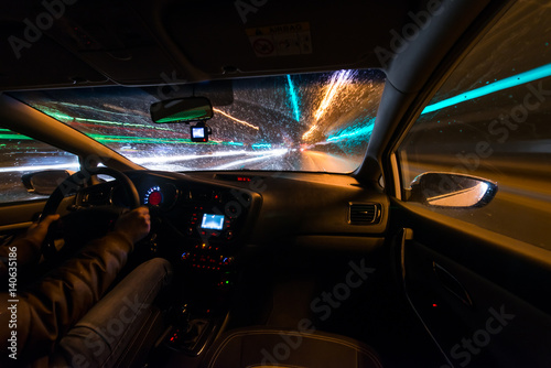 Night road view from inside car natural light street and other cars is motion blurred  during a rain