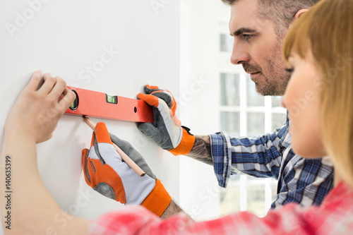 Couple marking on wall with level in new house