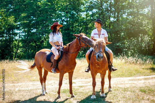 Beautiful young loving couple on horseback riding in nature