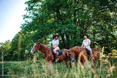 Beautiful young loving couple on horseback riding in nature
