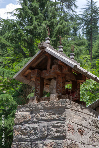MANALI, INDIA. A small Shiva Temple decorated with wood-carved a swastika and iron tridents.  Naggar, district of Kullu in Himachal Pradesh, India. © Estrellabuena
