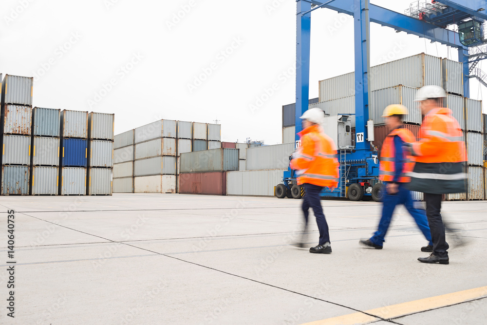 Full-length rear view of workers walking in shipping yard