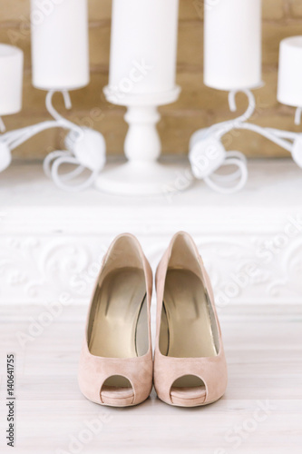 beige shoes of the bride in the white room and white candles a background