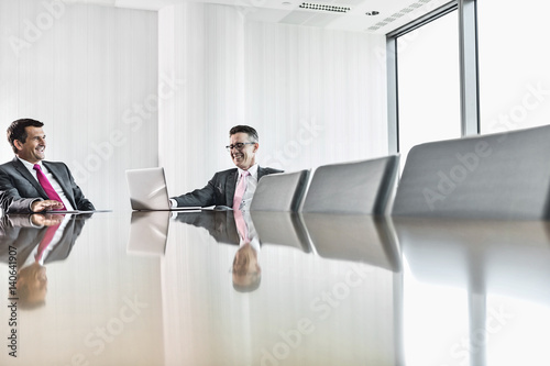 Smiling businessmen talking in conference room photo