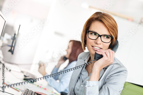 Young businesswoman talking on telephone at desk in office © moodboard