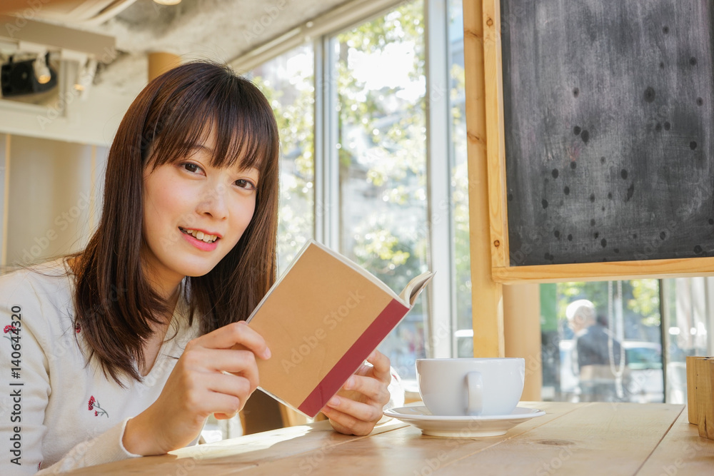カフェで読書をする若い女性