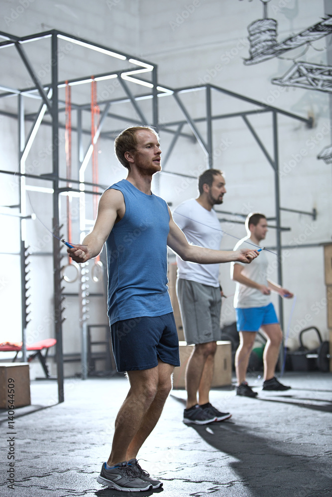 Full-length of men exercising in crossfit gym