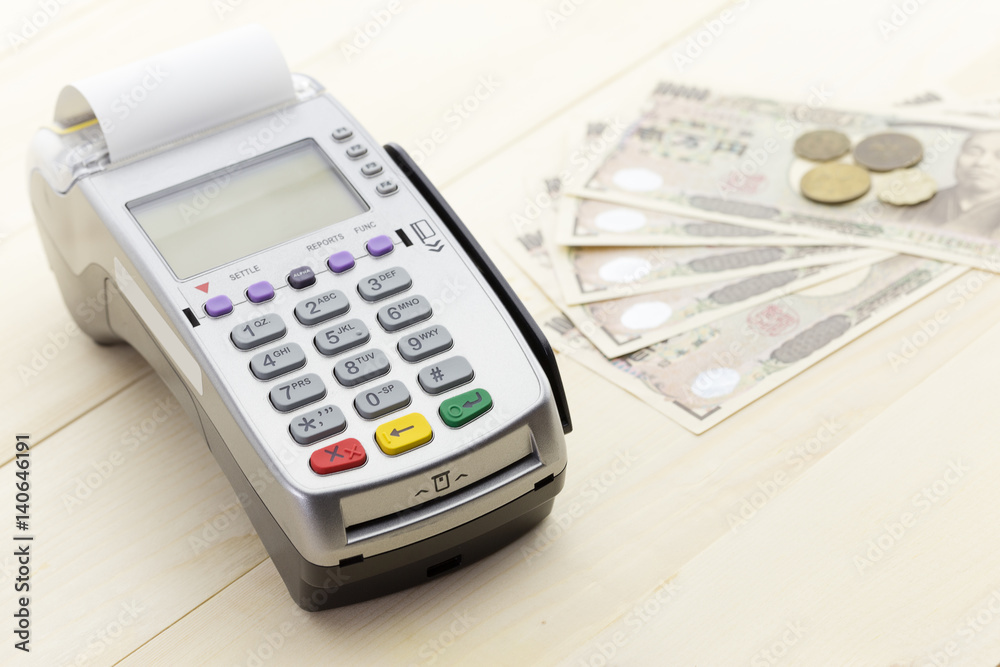 Credit Card Terminal or EDC on cashier wooden table in the store with japanese bank notes, pen, pencil and calculator. Credit Card Terminal or EDC on cashier wooden table in the store with japanese bank notes, pen, pencil and calculator.