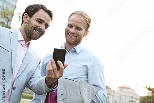 Businessmen using mobile phone against clear sky