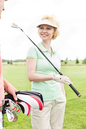 Happy woman looking at male friend at golf course