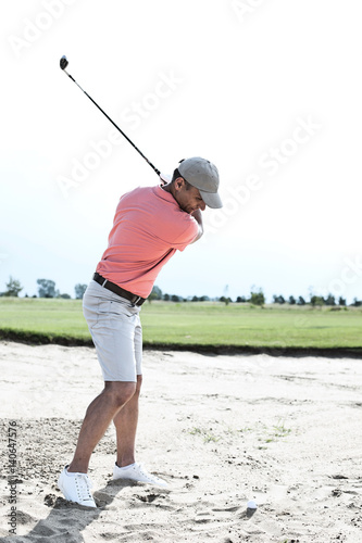 Middle-aged man swinging at golf course against clear sky