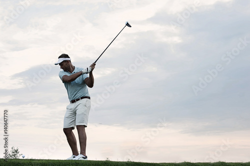 Obraz Dorosły mężczyzna bawić się golfa przeciw niebu