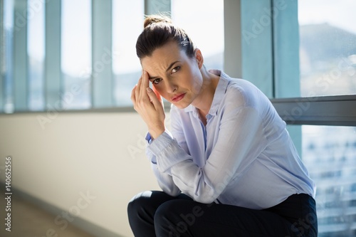 Free Download Tense female business executive sitting with hand on forehead - GFXLoad