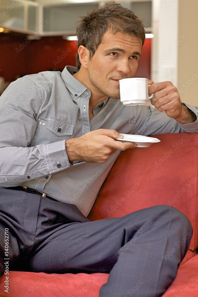 Young man drinking tea, sitting in sofa Young man drinking tea, sitting in sofa