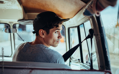 man sat in driving seat of a camper kombi van on a road trip