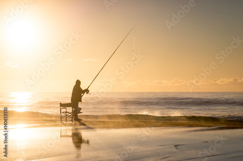 Fishermen with fishing rod at sunrise on beach