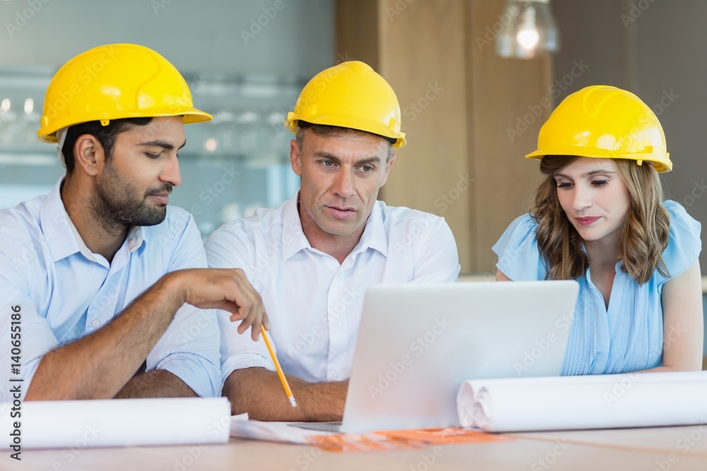 Architects discussing over laptop in conference room