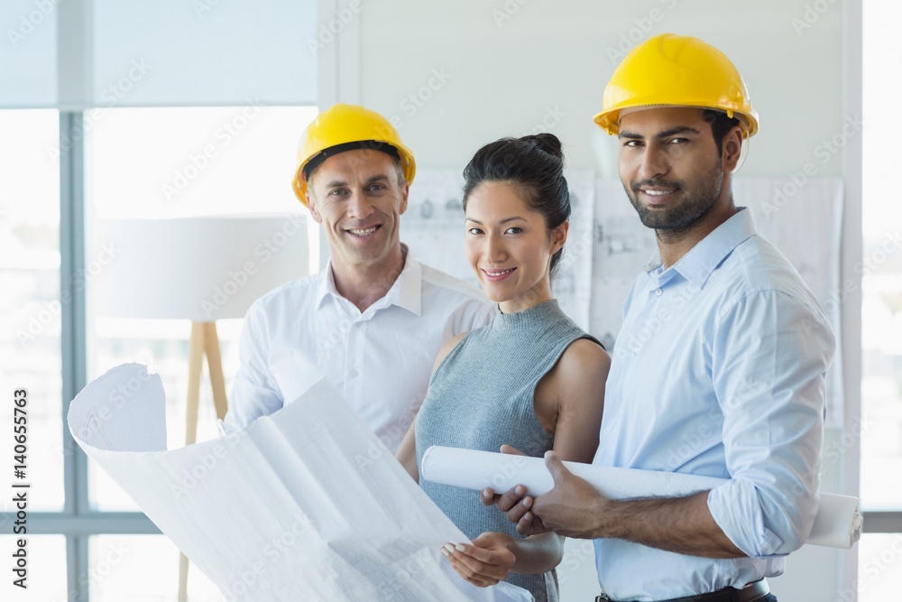 Smiling three architects standing in office with blueprint Smiling three architects standing in office with blueprint